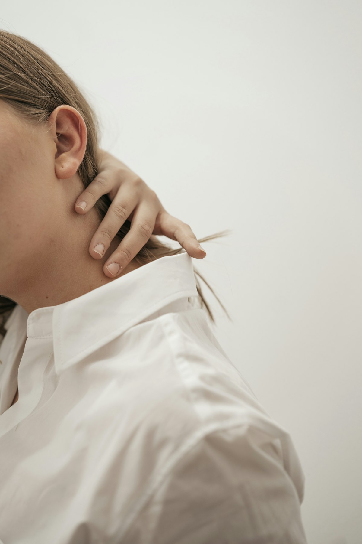 Person holding the back of their neck in discomfort, illustrating cervical neck pain